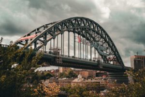 View of the historic Tyne Bridge in Newcastle upon Tyne, England amidst a cloudy sky.